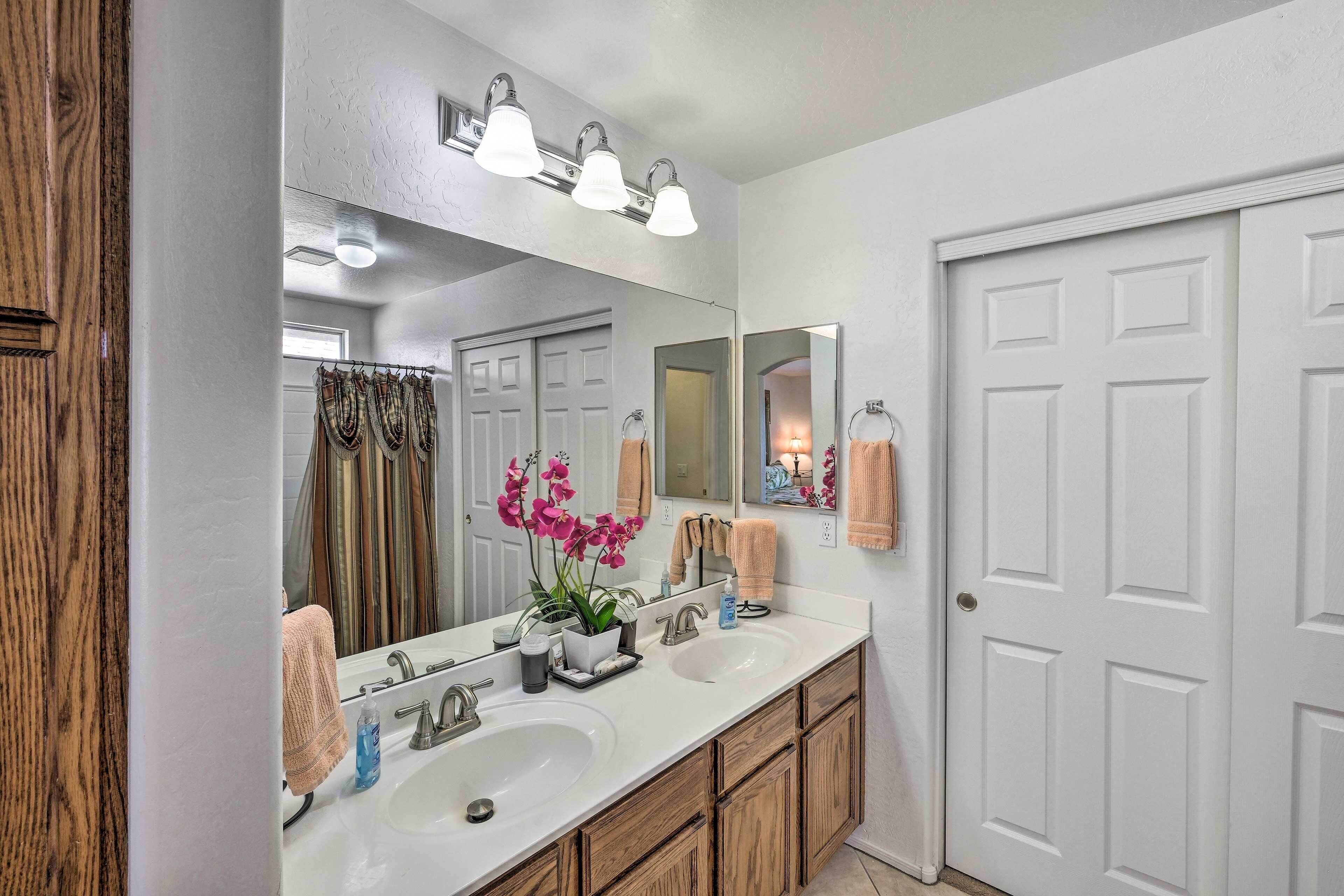 A bathroom with a double sink, wooden cabinets, a large mirror, and a towel rack.