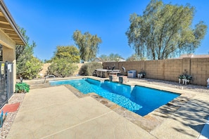 Relax by the pool surrounded by a patio with a geometric pattern and a tree-lined area with a pergola.