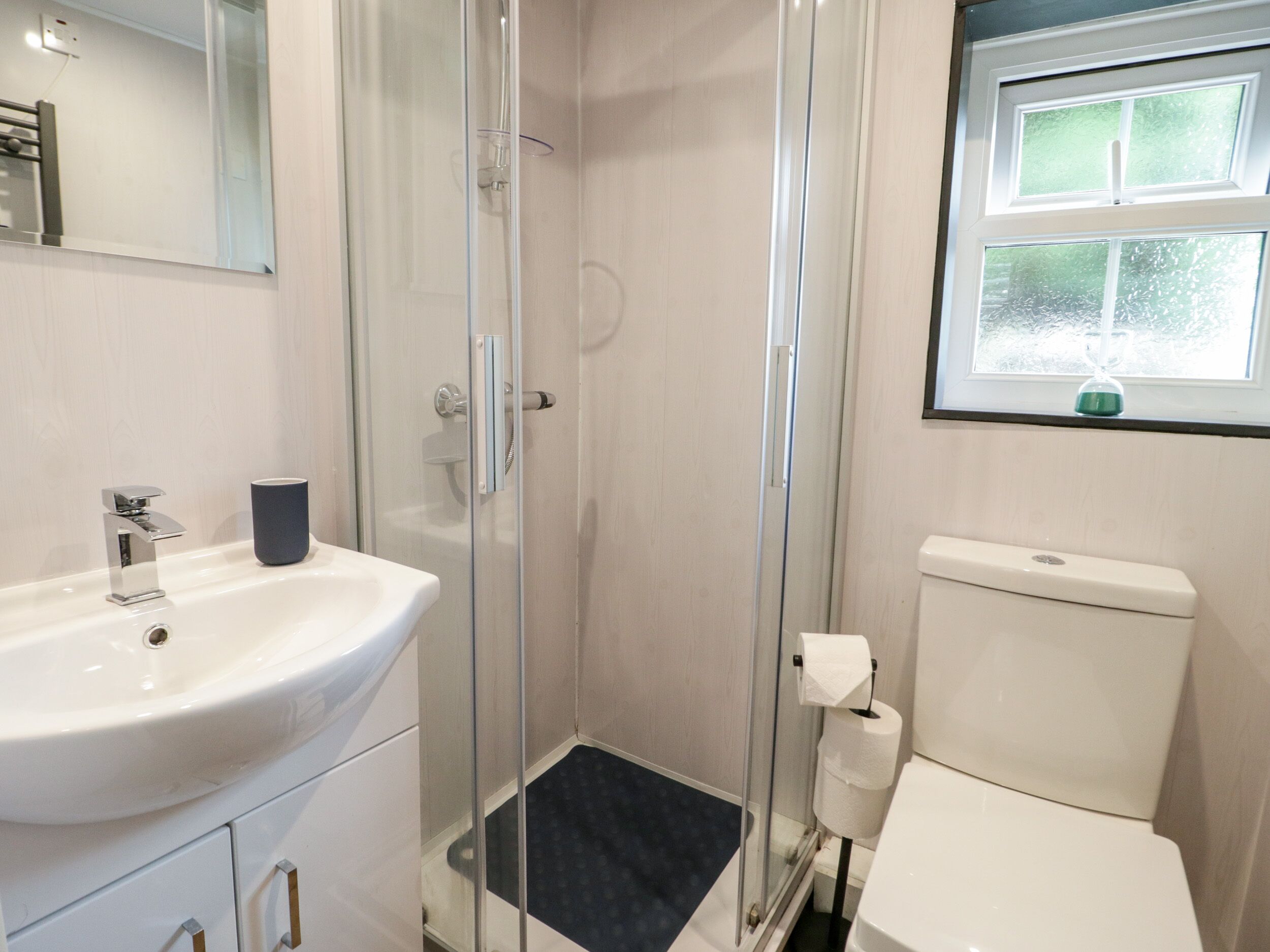 A bathroom with a glass-enclosed shower, a white sink, and a toilet.
