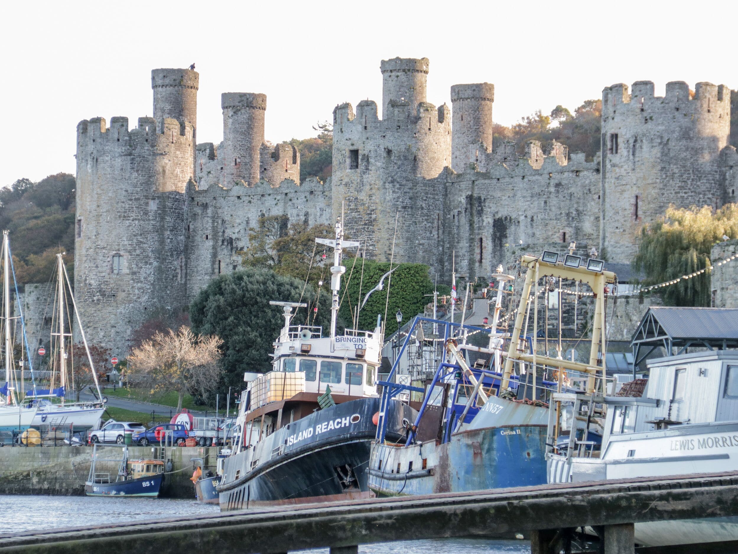 A historic castle with a moat and boats docked in front.