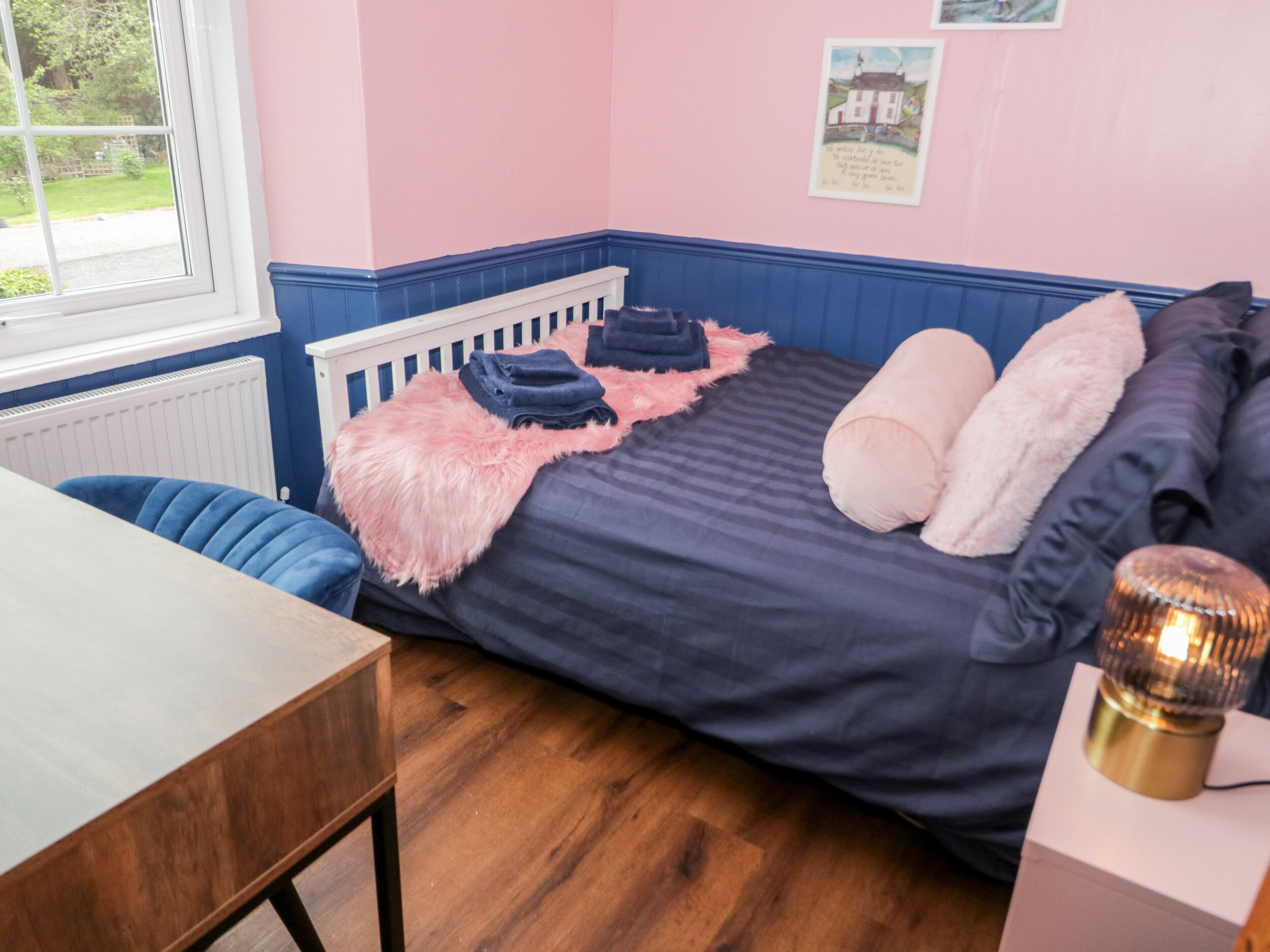 A bedroom with a bed, a desk, and a window.
