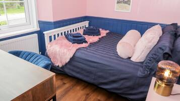 A bedroom with a bed, a desk, and a window.