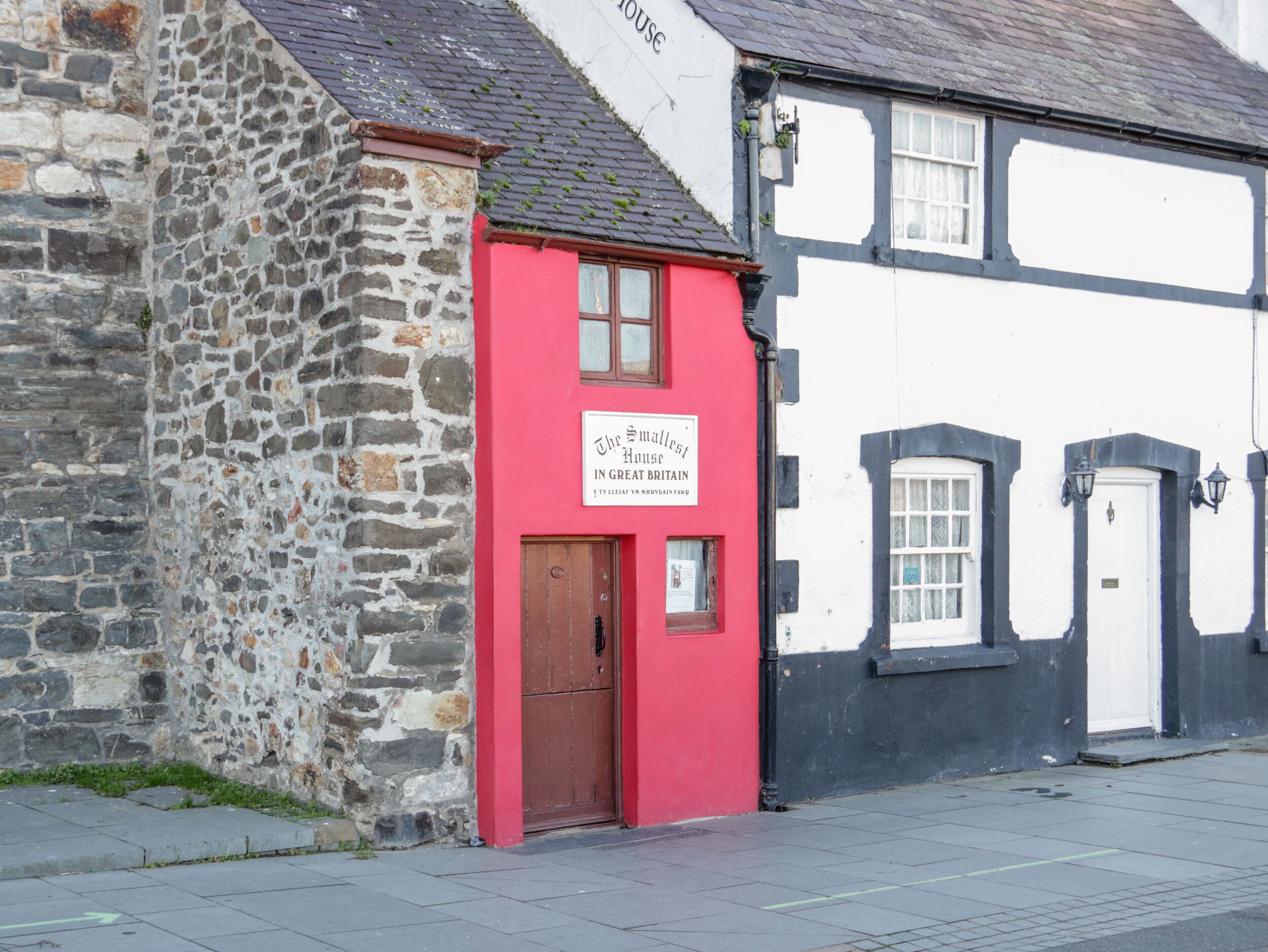 A traditional stone building with a red door and a sign that reads "The Smallest House in Great Britain."