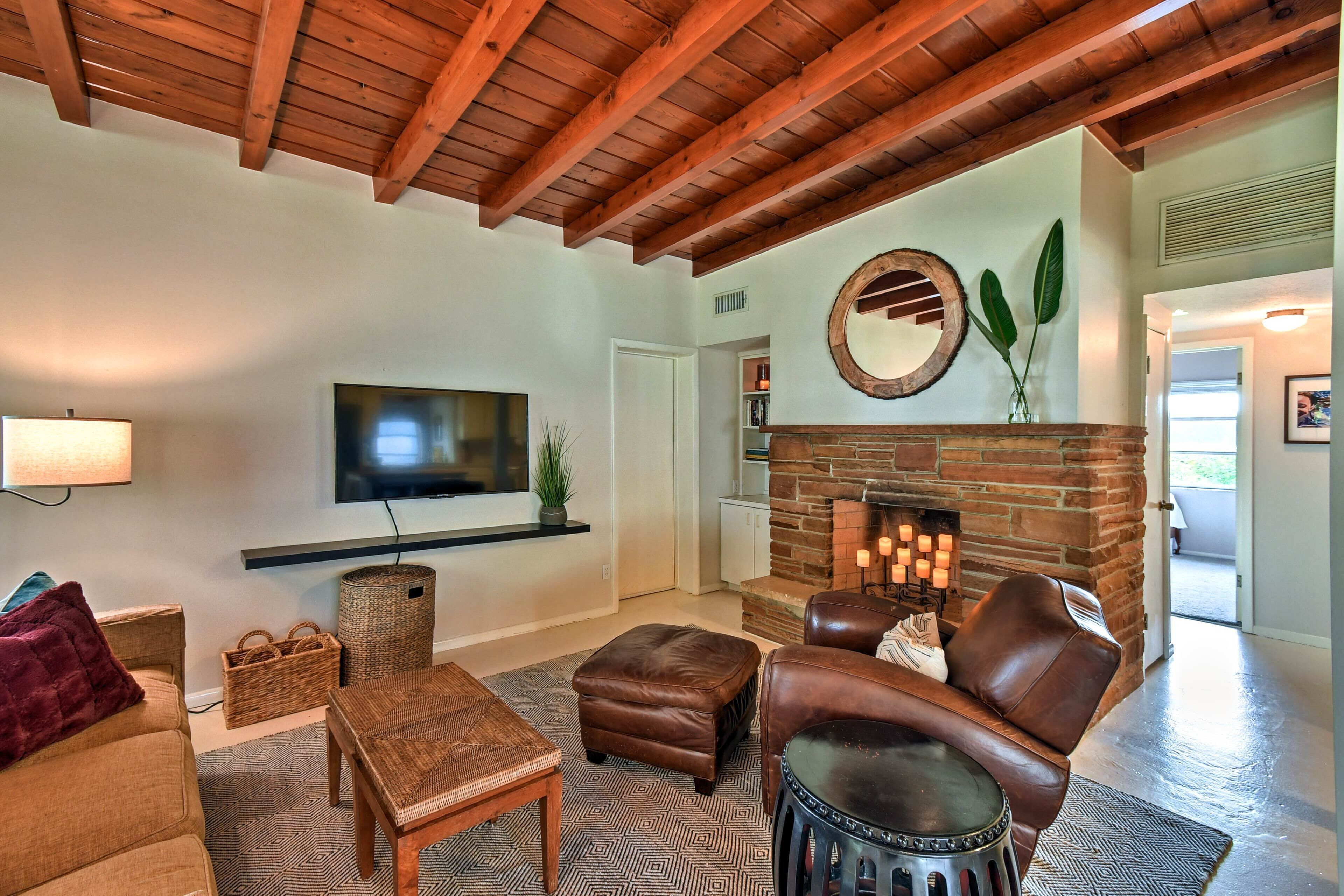Una sala de estar acogedora con chimenea, muebles de cuero y un televisor instalado en la pared.