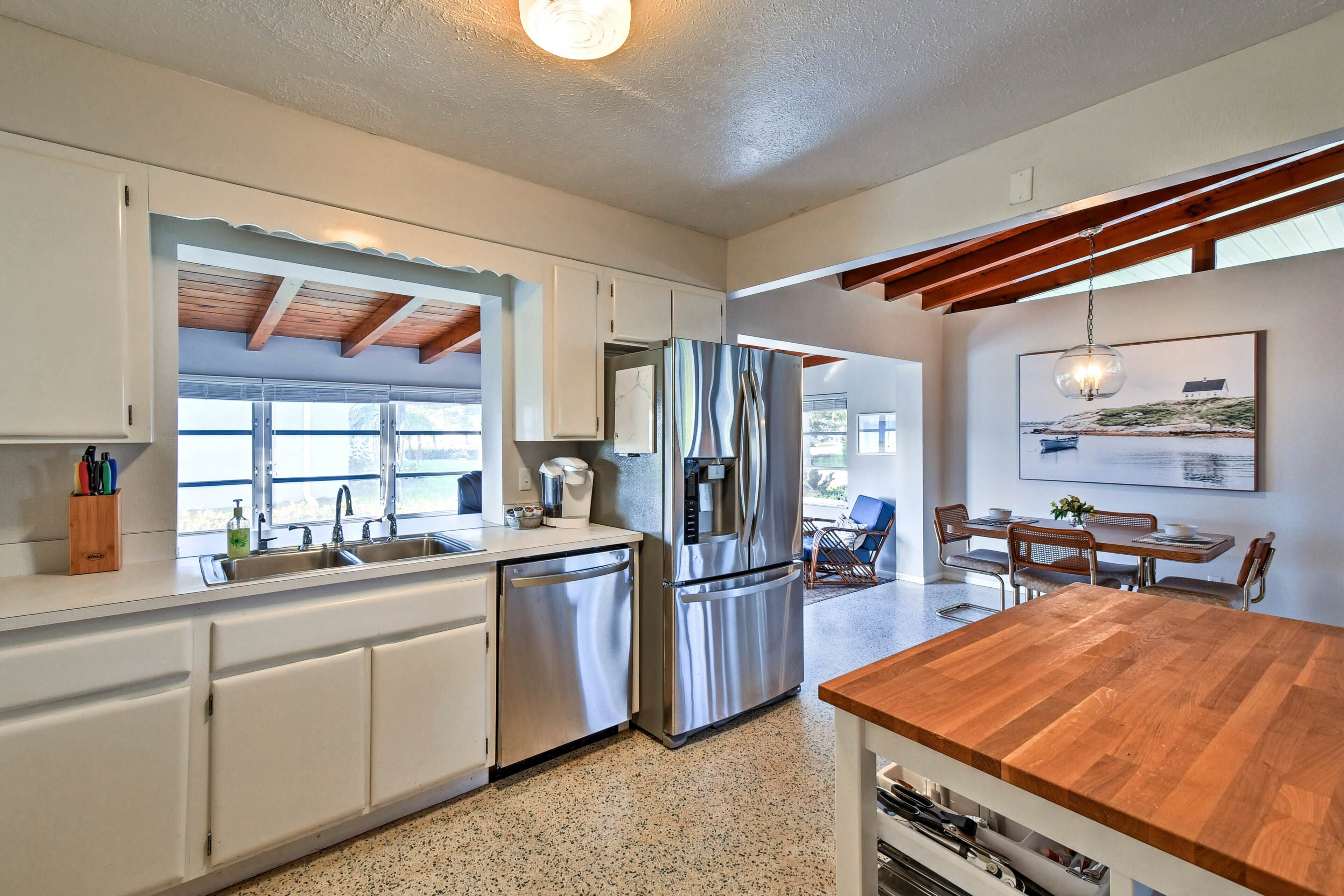 Una cocina moderna con electrodomésticos de acero inoxidable, armarios blancos y una isla de madera.