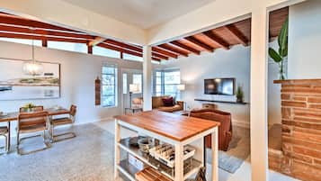 Amplia sala de estar con una mesa de comedor de madera, un sofá y un televisor.