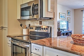 A kitchen with stainless steel appliances, a granite countertop, and white cabinetry. - Ormond Beach Bungalow w/ Patio & Quiet Setting! (Ormond Beach)
