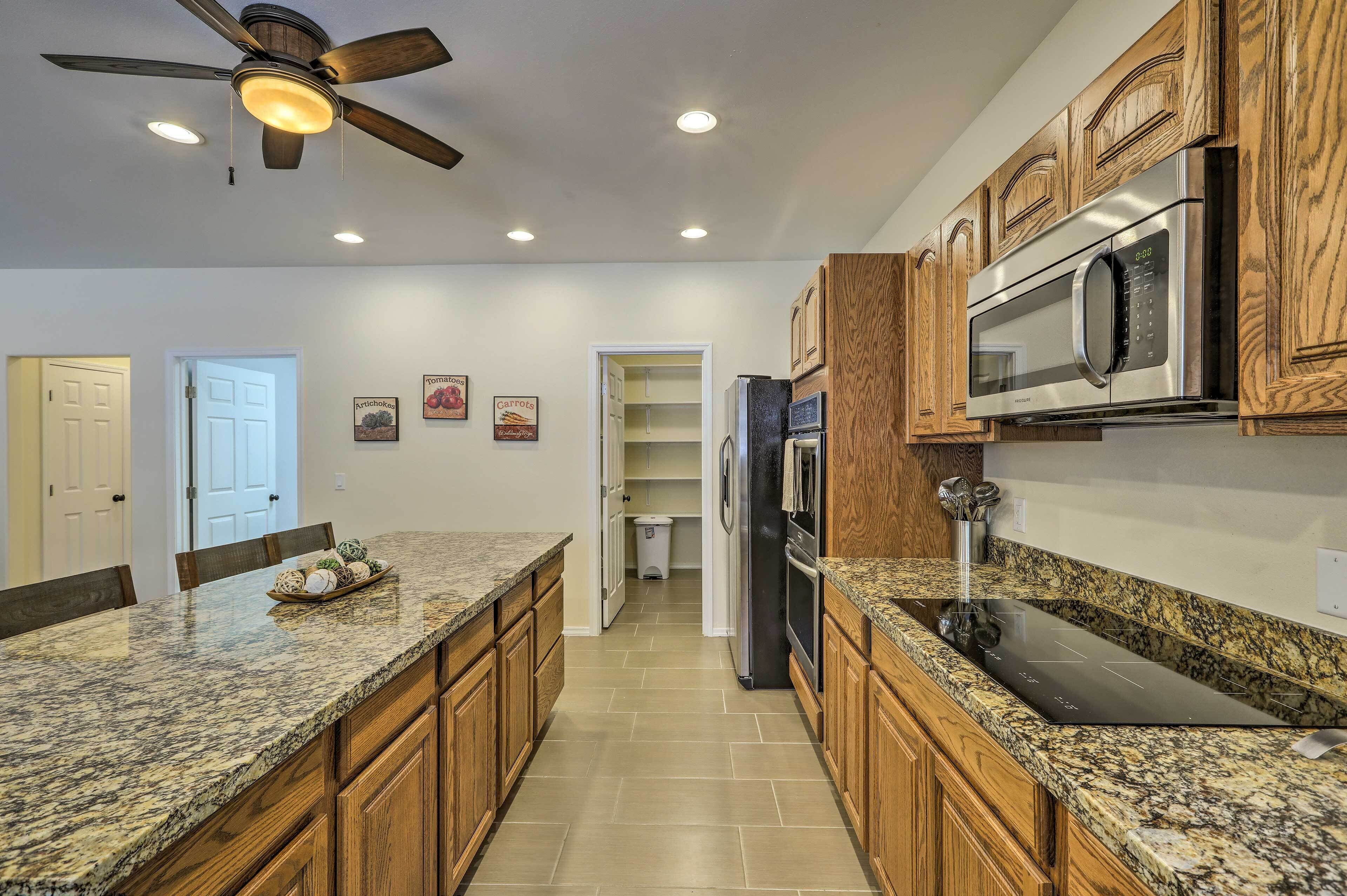 A kitchen with granite countertops, wooden cabinets, a stainless steel refrigerator, and a microwave.