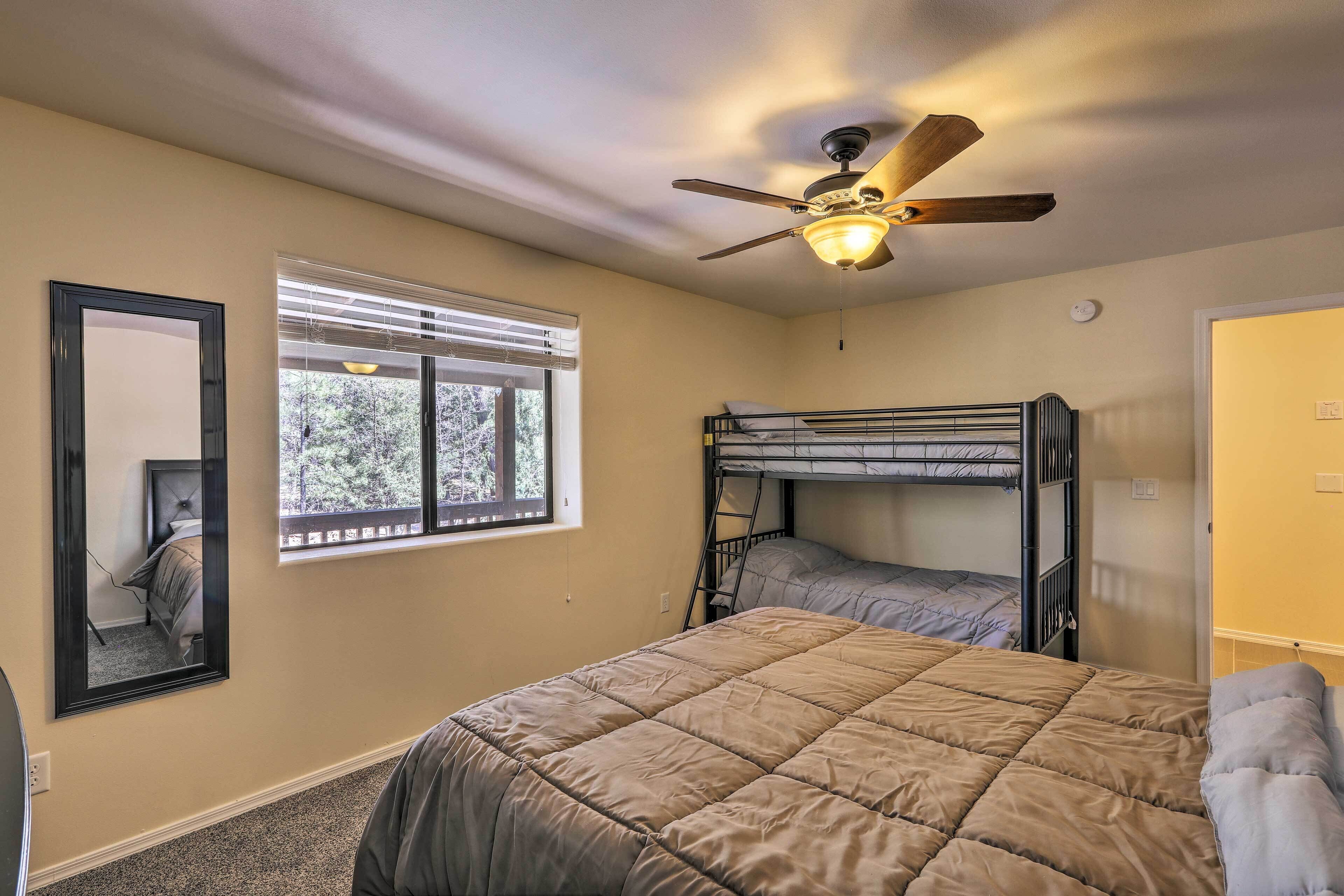 A bedroom with a bunk bed, a ceiling fan, a window with blinds, and a door.