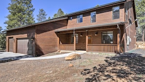 Ein zweistöckiges Holzhaus mit überdachter Veranda, Garage und einem gepflegten Vorgarten mit Bepflanzung.