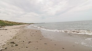 A beach with a sandy shore and gentle waves. - On The Watersedge (Chathill)