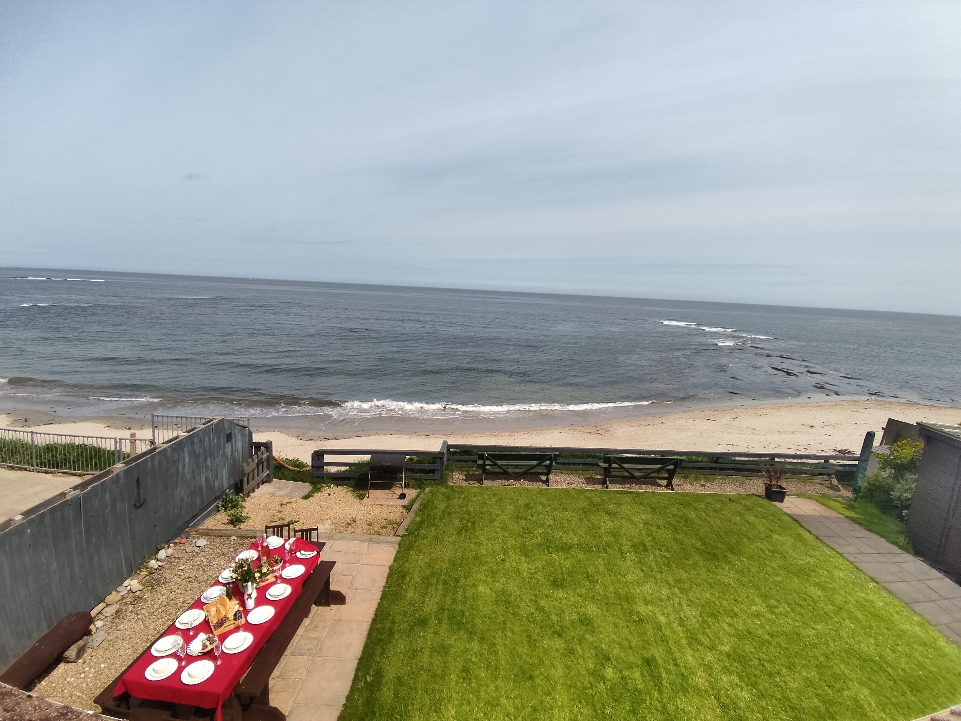 Un comedor con una mesa dispuesta para seis personas, con vista a una playa y olas.