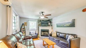A living room with leather sofas, a wooden coffee table, a fireplace, and a ceiling fan.
