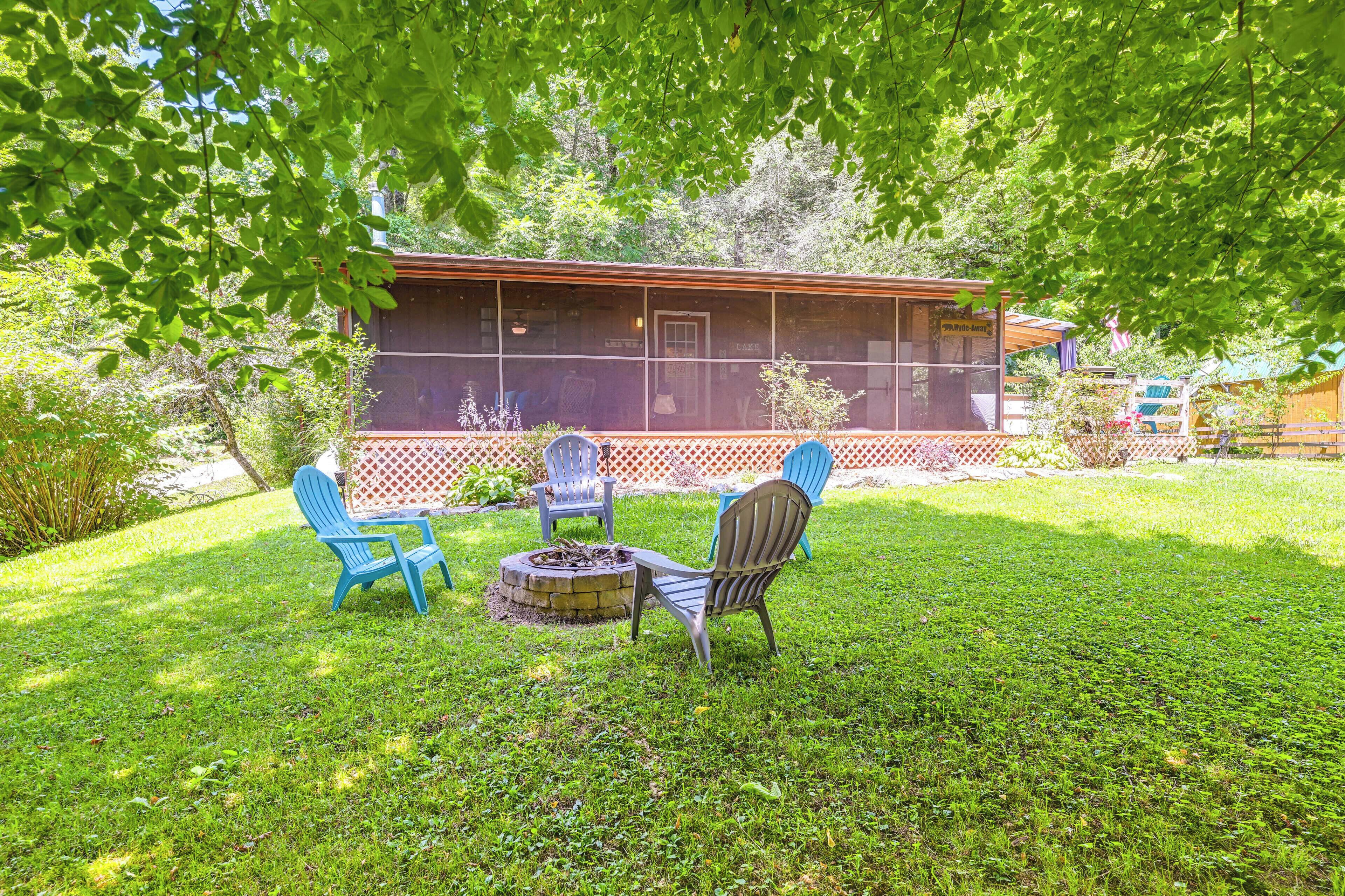 A backyard with a covered patio, outdoor seating, and a fire pit.