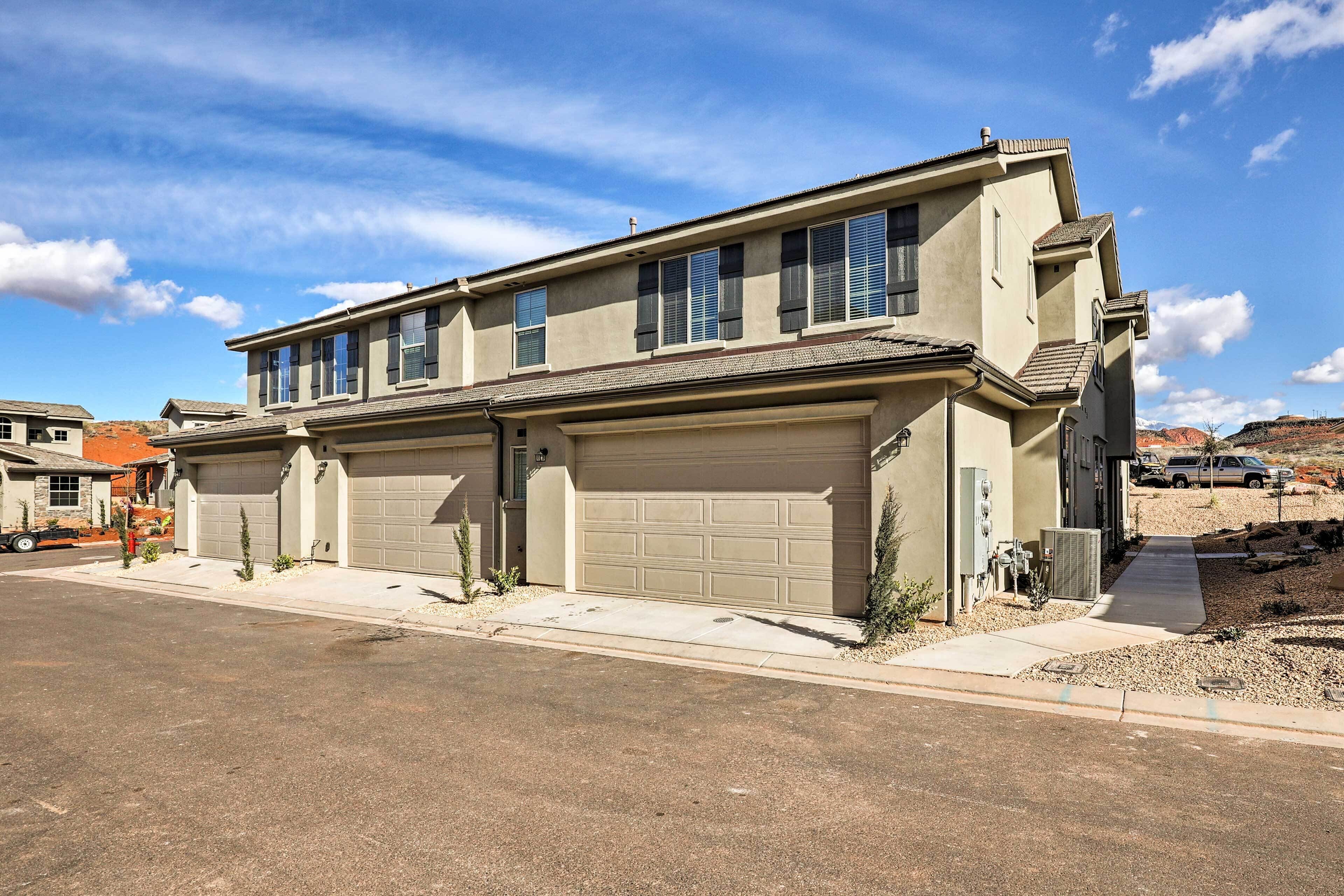 A two-story residential building with a garage, a driveway, and a clear sky.