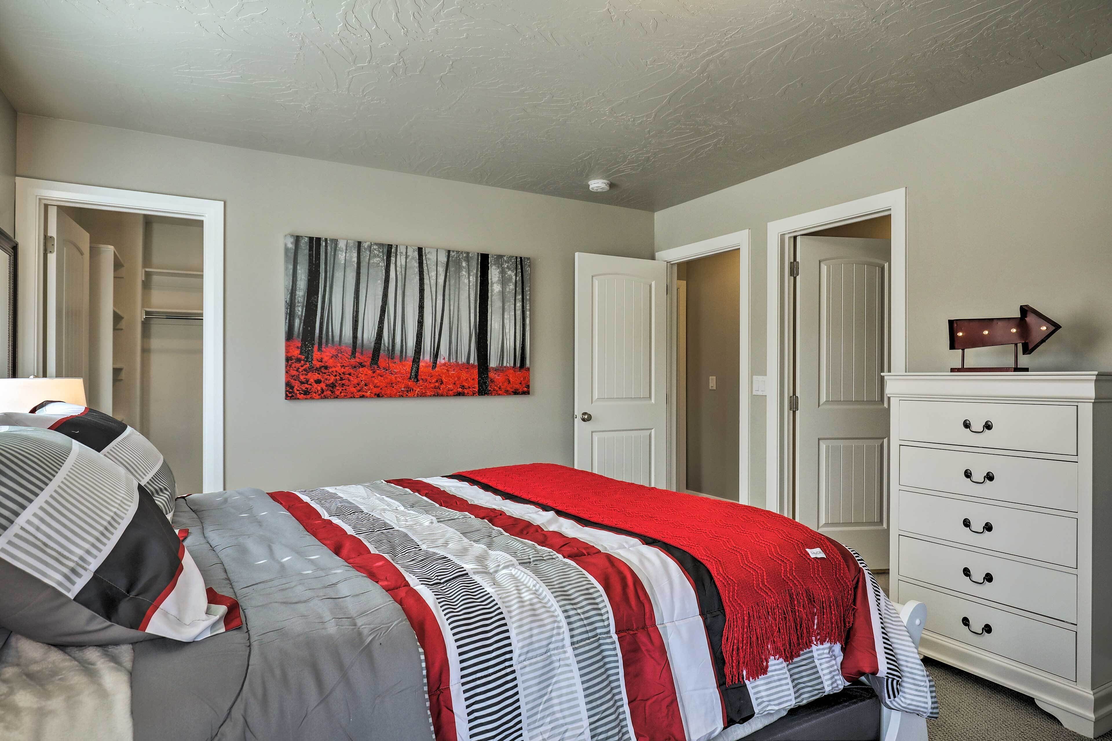 A bedroom with a bed, a dresser, a closet, and a painting on the wall.