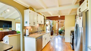 Une cuisine moderne avec des meubles blancs, des appareils en acier inoxydable et un plancher en bois.