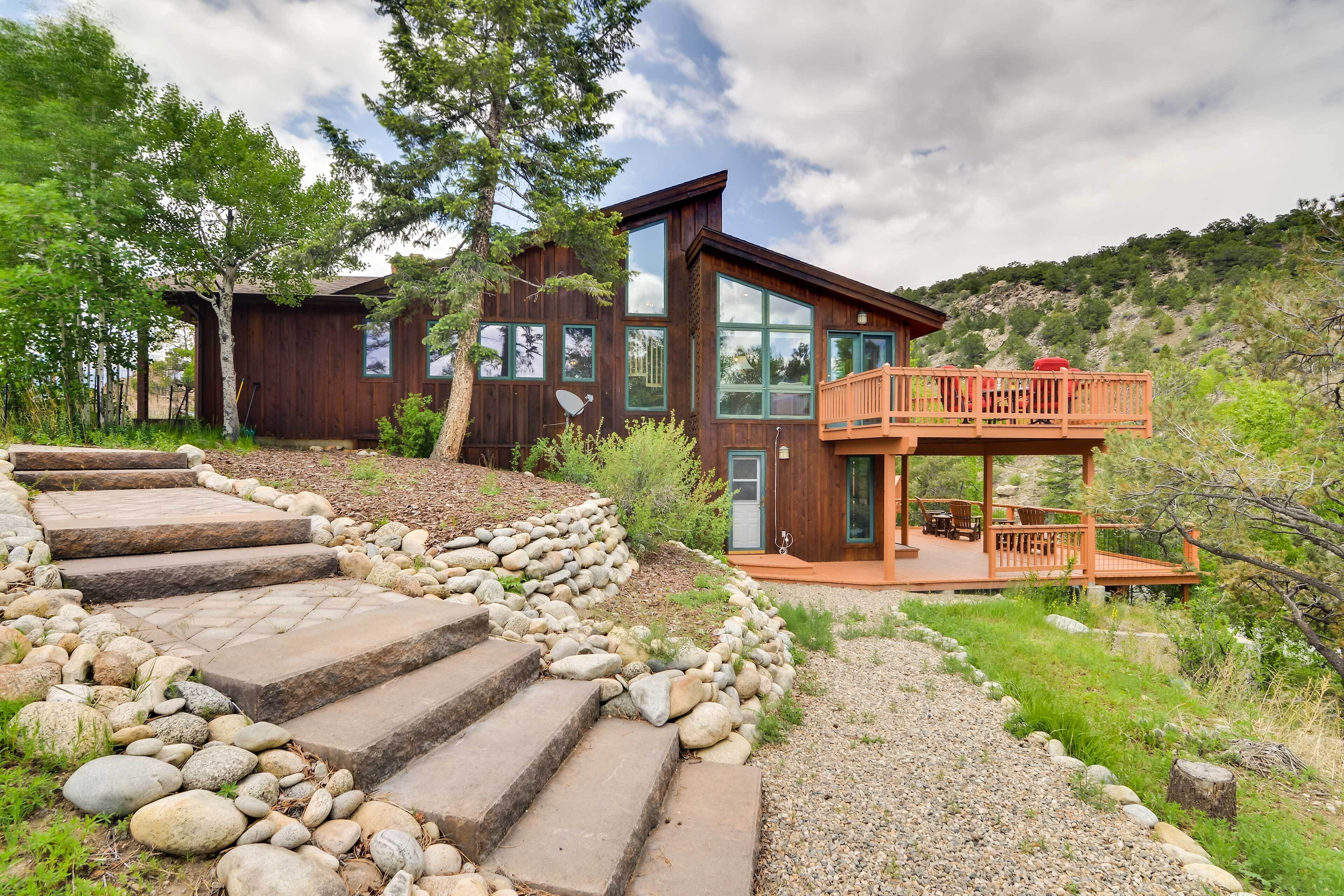 A modern wooden cabin with a deck and stone steps leading to the entrance.