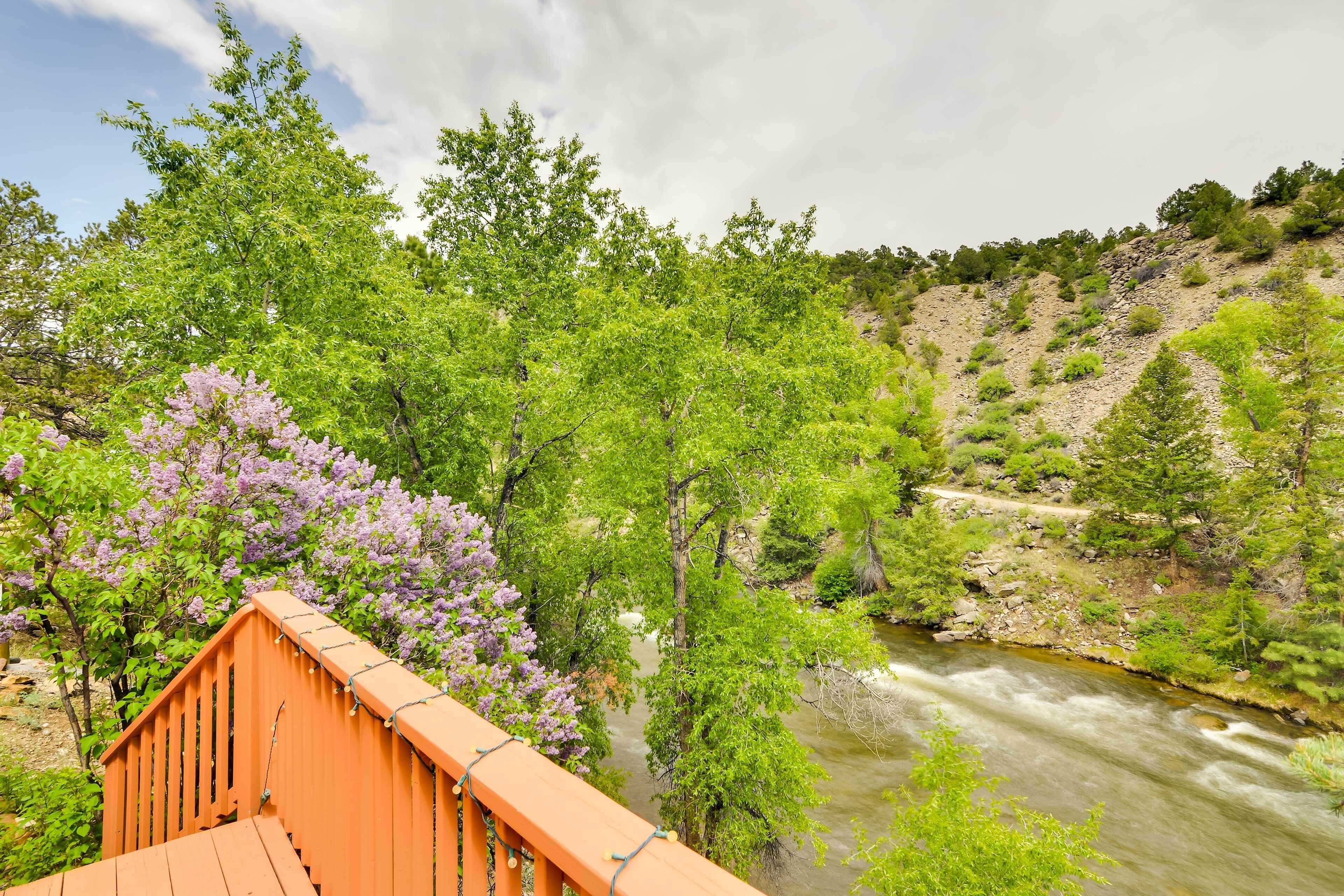 A wooden bridge over a river with lush greenery and trees.