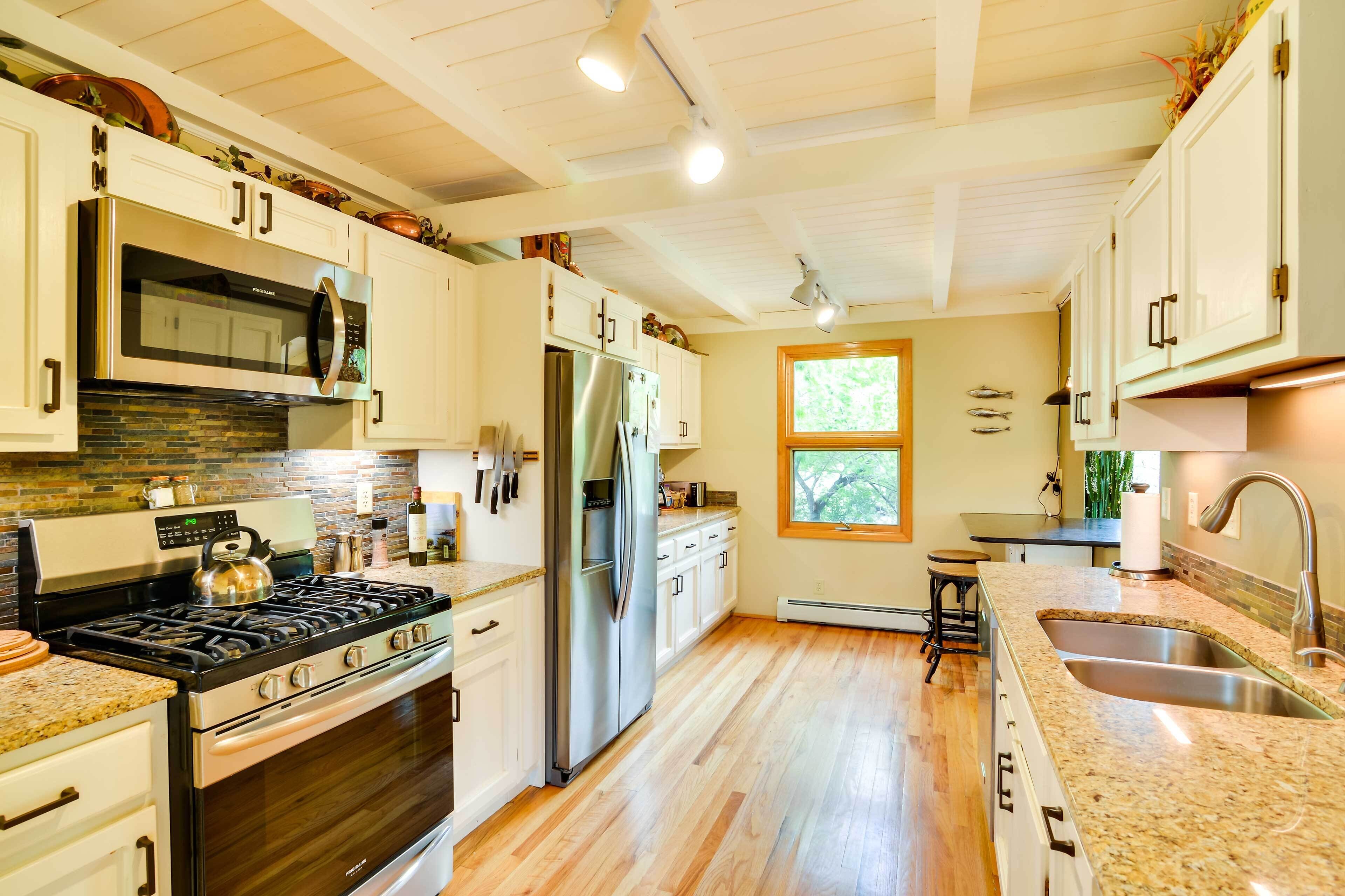 A kitchen with white cabinets, stainless steel appliances, and a granite countertop.