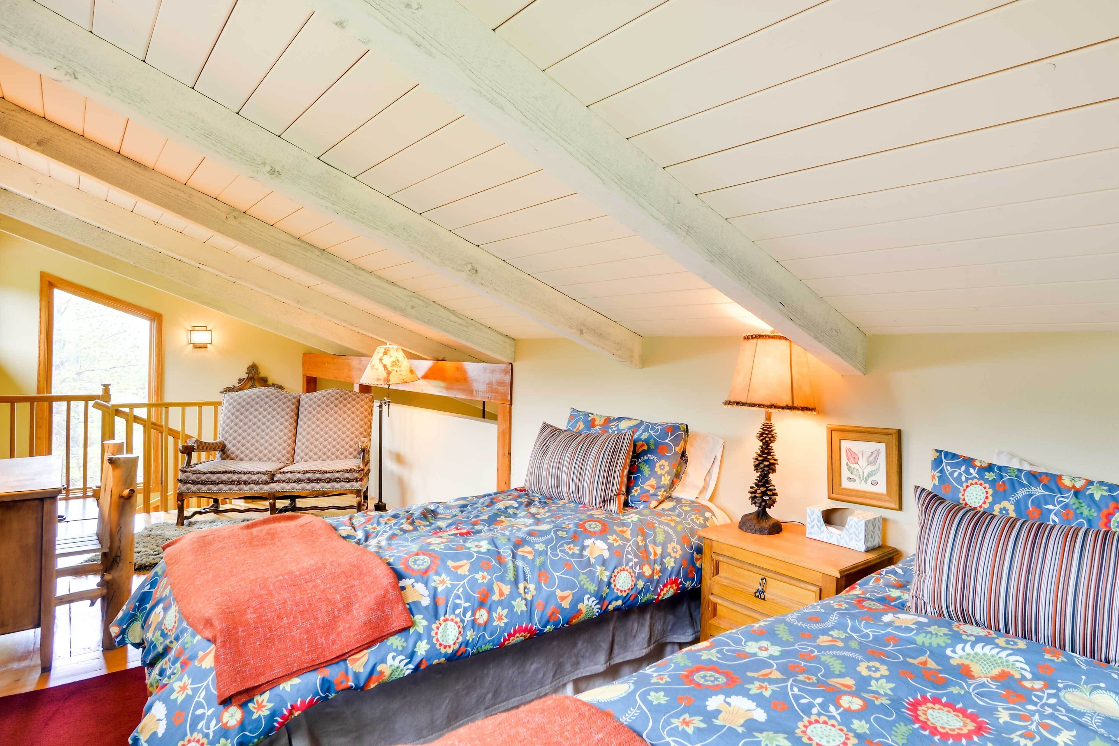 Ein gemütliches Schlafzimmer mit zwei Betten, einem Holzstuhl, einem Nachttisch und einer Treppe, die zu einer oberen Ebene führt.