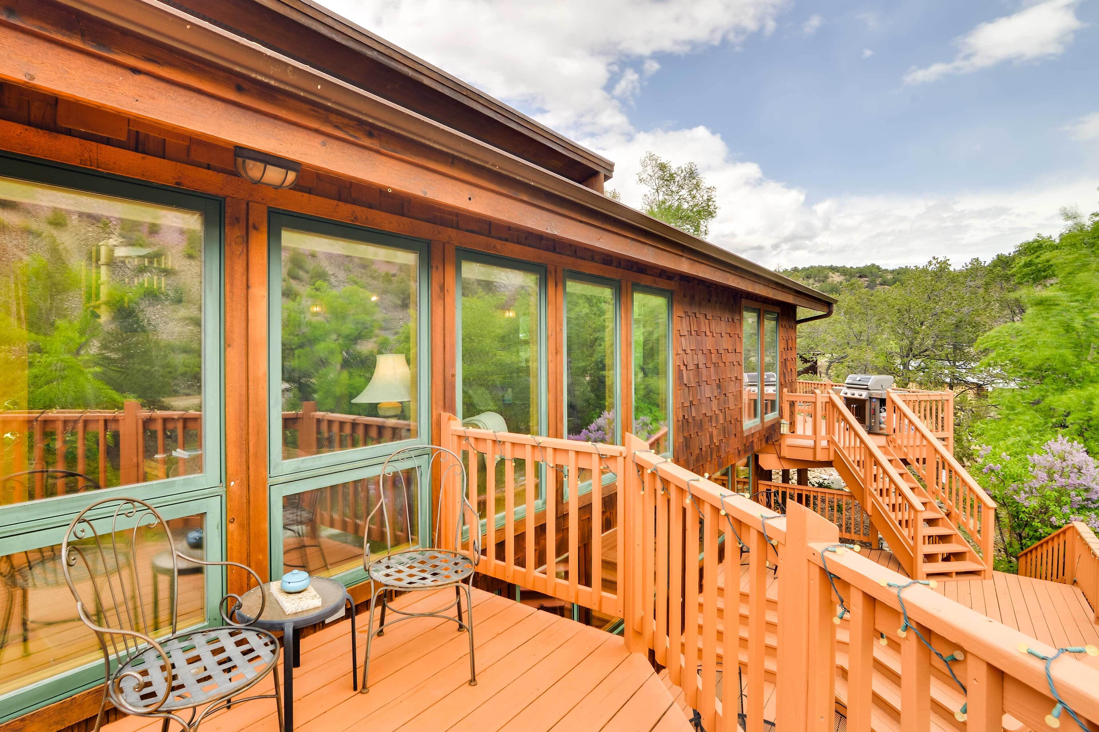 Une terrasse en bois avec une rambarde, une table et deux chaises.