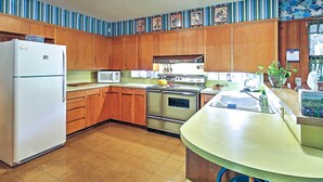 A kitchen with wooden cabinets, a white refrigerator, a stove, and a microwave. - Mid-century Hideaway: Spacious Brownsville Home! (Brownsville)