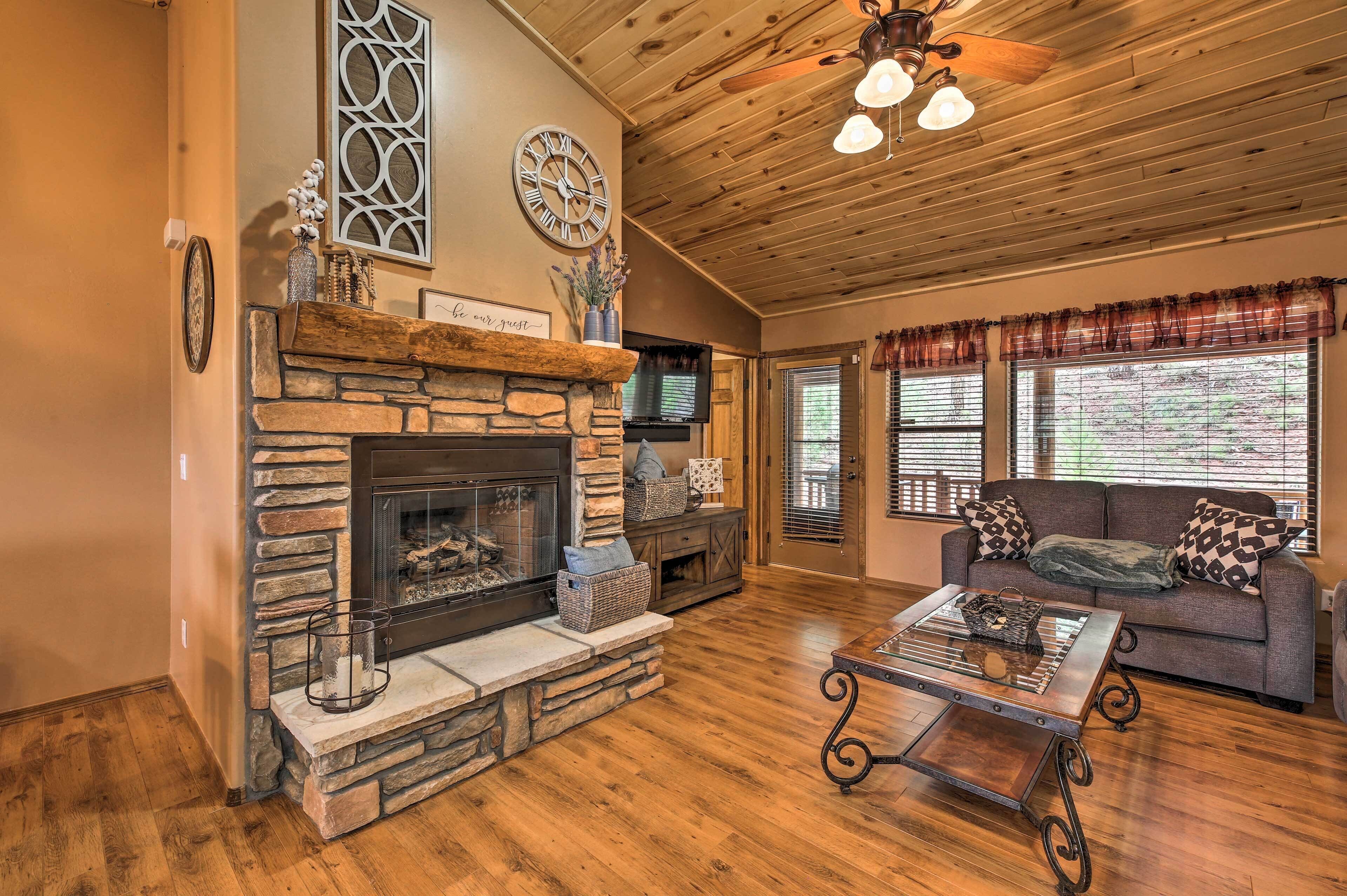 A cozy living room with a stone fireplace, wooden ceiling, and a comfortable sofa.