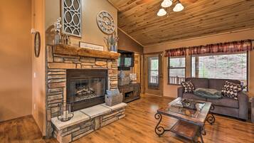 A cozy living room with a stone fireplace, wooden ceiling, and a comfortable sofa.