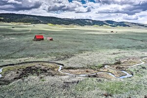 Un paisaje rural con un granero rojo, campos abiertos y un canal de agua serpenteante.