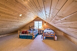 Un dormitorio abrigado en un ático con dos camas de madera, una ventana y una lámpara.