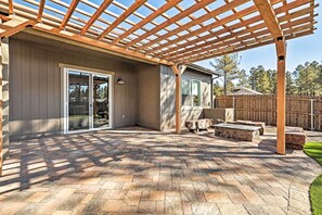 A covered patio with a pergola, stone tiles, and a wooden fence.