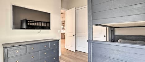 A hallway with a dark wooden dresser, a mounted TV, and a bed with a headboard.