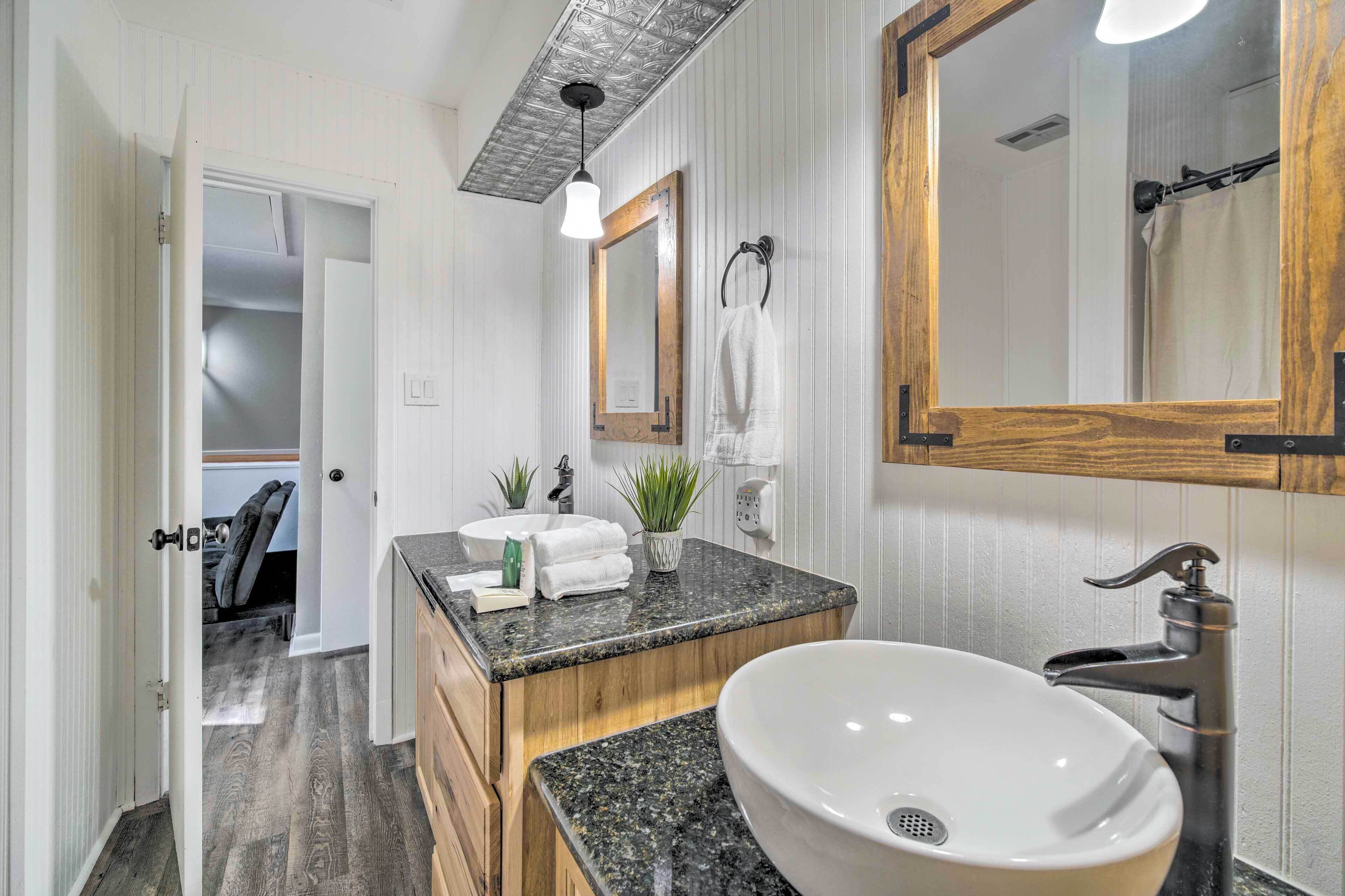 A modern bathroom with a large sink, wooden vanity, and a mirror.