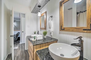 Ein modernes Badezimmer mit einem großen Waschbecken, einem Holz-Waschtisch und einem Spiegel.