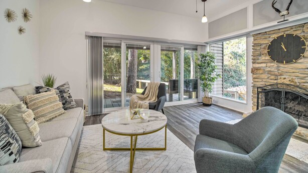 A spacious living room with a large window, a stone fireplace, and a modern chandelier. - Coldspring Cottage < 1 Mi to Lake Livingston! (Coldspring)
