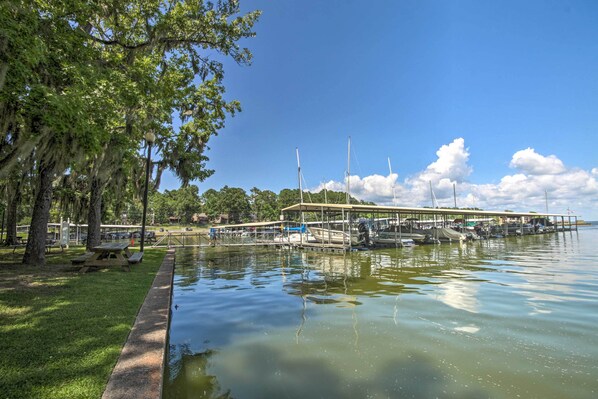 A marina with docked boats, a covered picnic area, and a grassy park area with trees. - Coldspring Cottage < 1 Mi to Lake Livingston! (Coldspring)