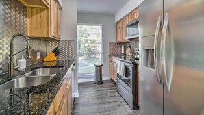 A modern kitchen with wooden cabinets, stainless steel appliances, and a large window. - Coldspring Cottage < 1 Mi to Lake Livingston! (Coldspring)