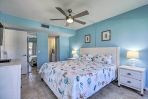 A bedroom with a bed, two bedside tables, a ceiling fan, and a door leading to another room. - Sweet Snowbird Escape ~ 2 Mi to St Pete Beach (St. Petersburg)