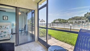 A balcony with a glass door leading to a bedroom, a pool, and a grassy area with a pergola. - Sweet Snowbird Escape ~ 2 Mi to St Pete Beach (St. Petersburg)