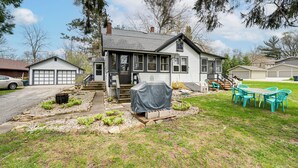 Ein zweigeschossiges Haus mit Garage, Grillhaus und einer Terrasse mit Sitzgelegenheiten.