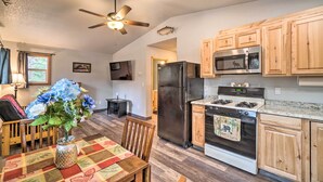 A kitchen with wooden cabinets, a refrigerator, microwave, stove, and a dining area with a table and chairs.