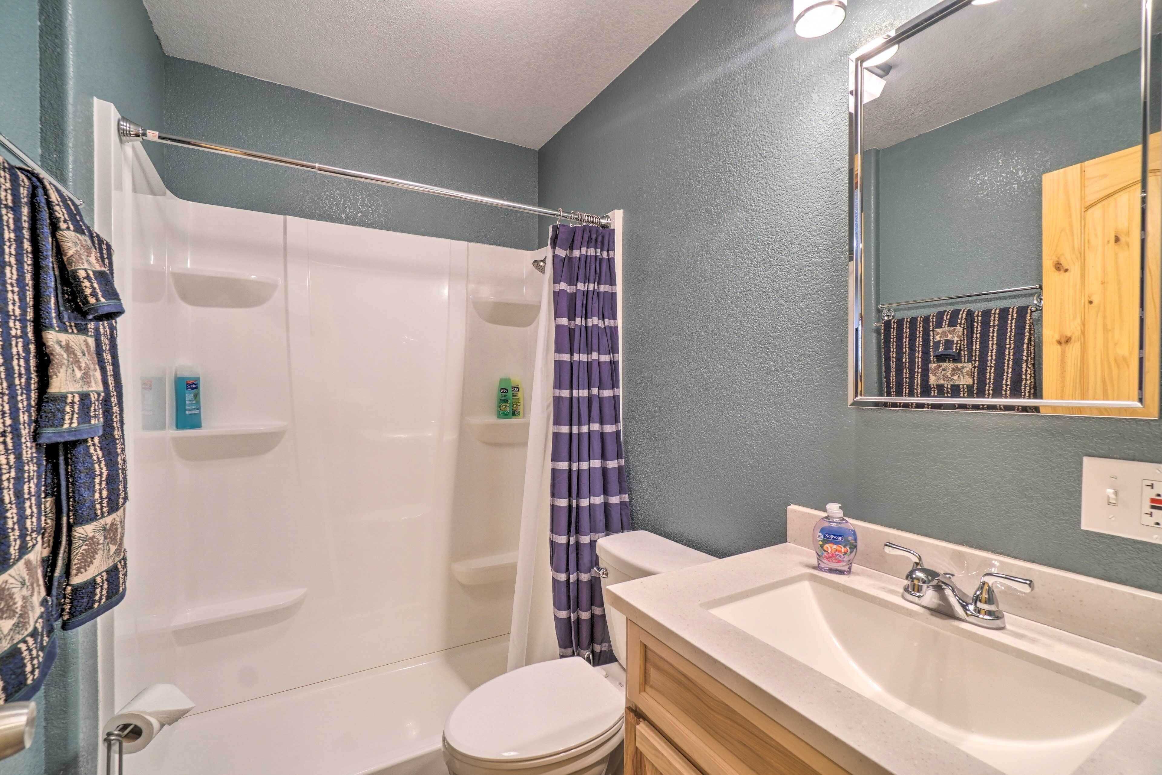 A bathroom with a shower, toilet, sink, and a mirror.