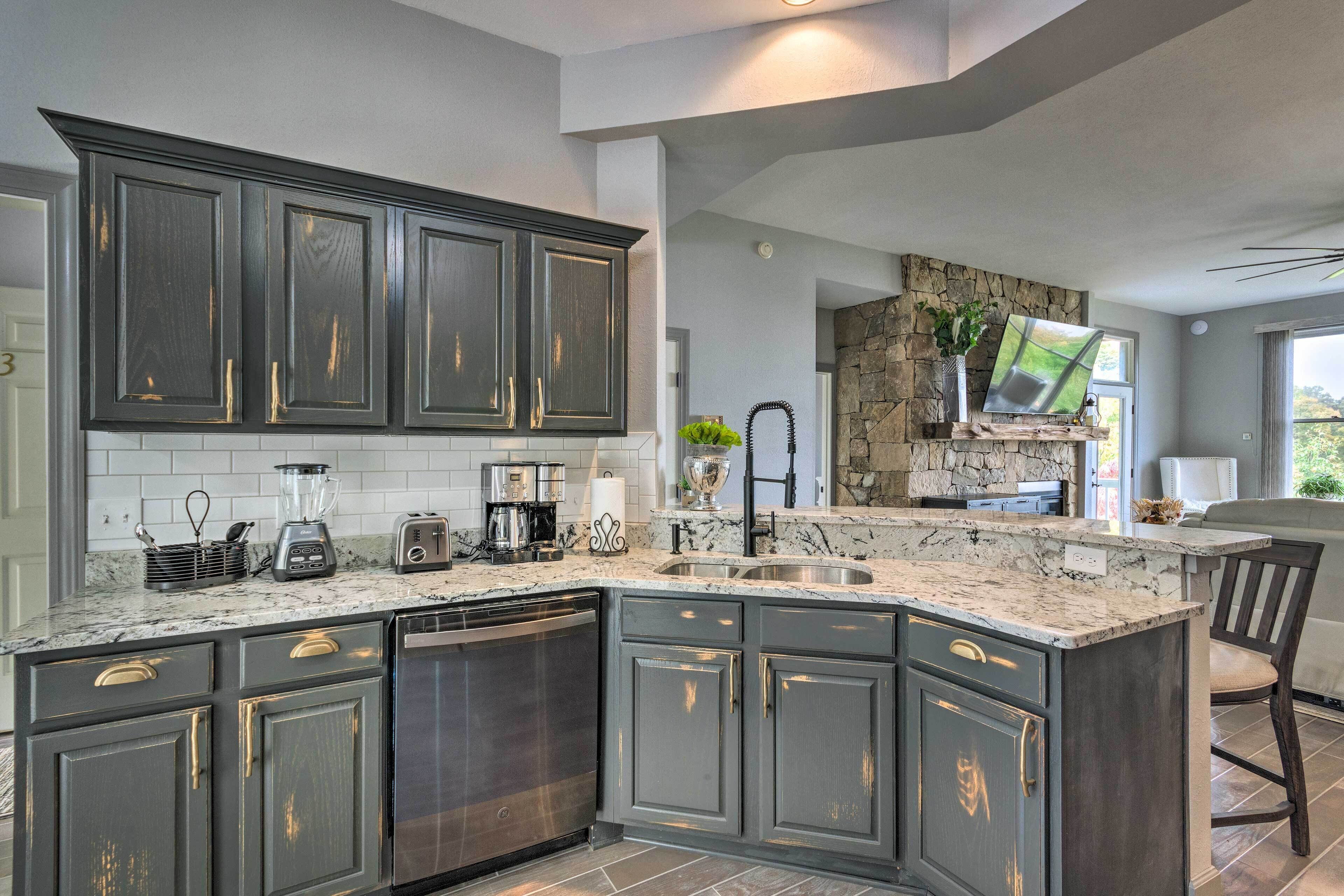 A kitchen with dark cabinets, a granite countertop, a dishwasher, a sink, and a stone accent wall.