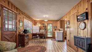 A compact kitchen with wooden walls, a dining area with a table and chairs, and a small refrigerator. - Tonto Nat'l Forest Riverside Cabin! (Payson)