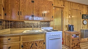A kitchen with wooden cabinets, a stove, and a sink. - Tonto Nat'l Forest Riverside Cabin! (Payson)