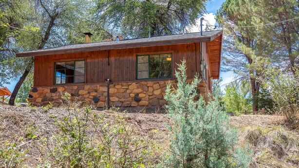 A rustic cabin with a stone foundation, wooden walls, and a large window. - Tonto Nat'l Forest Riverside Cabin! (Payson)