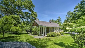 Ein eingeschossiges Haus mit Satteldach, umgeben von üppigen, grünen Bäumen und einem gepflegten Rasen.