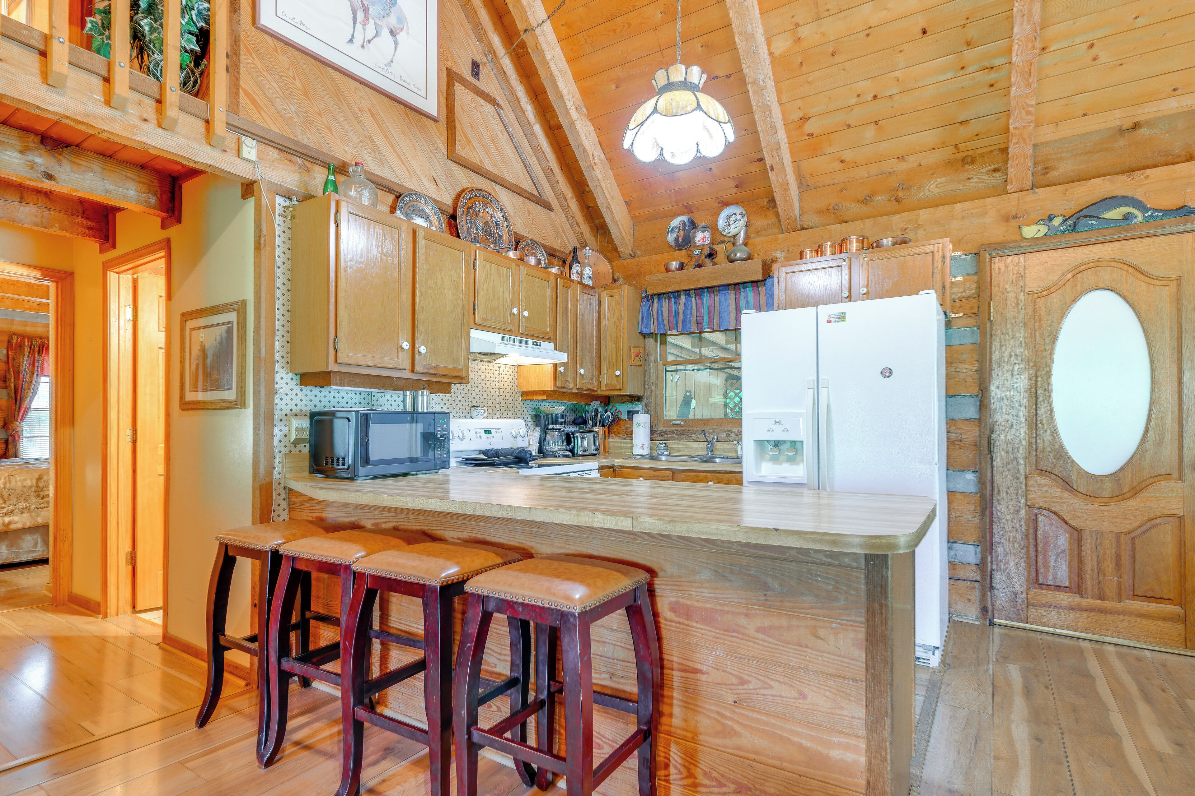A wooden kitchen with a central island, bar stools, and a refrigerator.