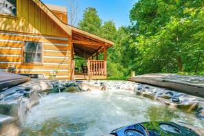 Eine Holzhütte mit Whirlpool und überdachter Veranda.